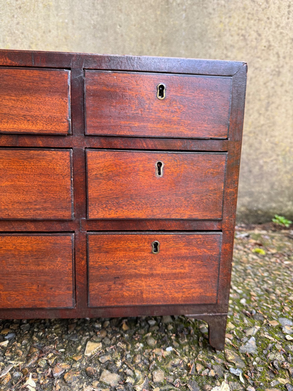 A dark Georgian mahogany flight of nine drawers with brass keyhole escutcheons resting on short bracket feet. View VI
