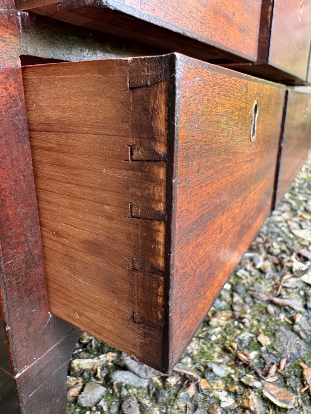 A dark Georgian mahogany flight of nine drawers with brass keyhole escutcheons resting on short bracket feet. View X