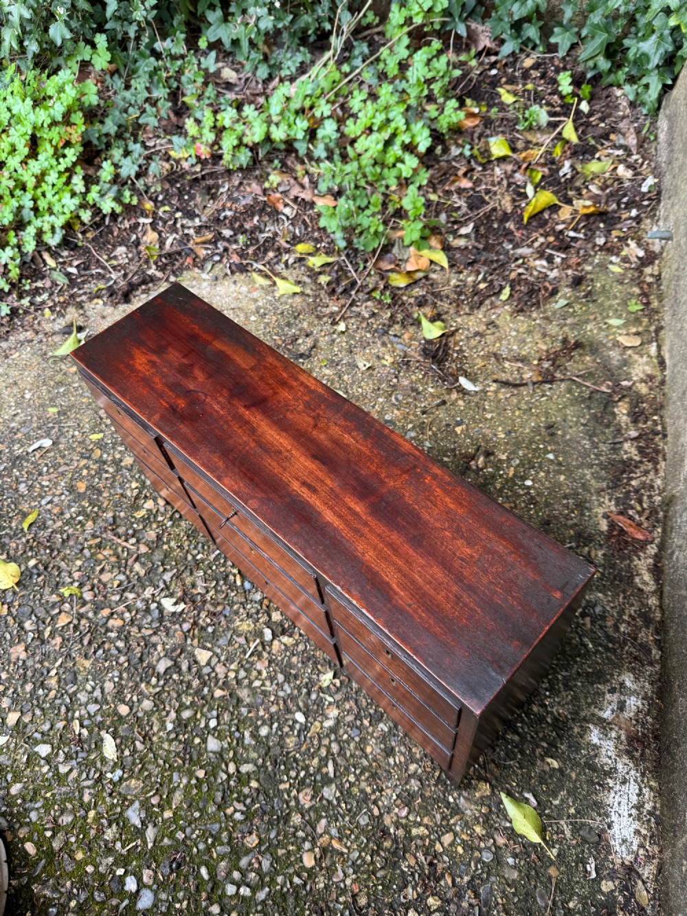 A dark Georgian mahogany flight of nine drawers with brass keyhole escutcheons resting on short bracket feet. View XIII