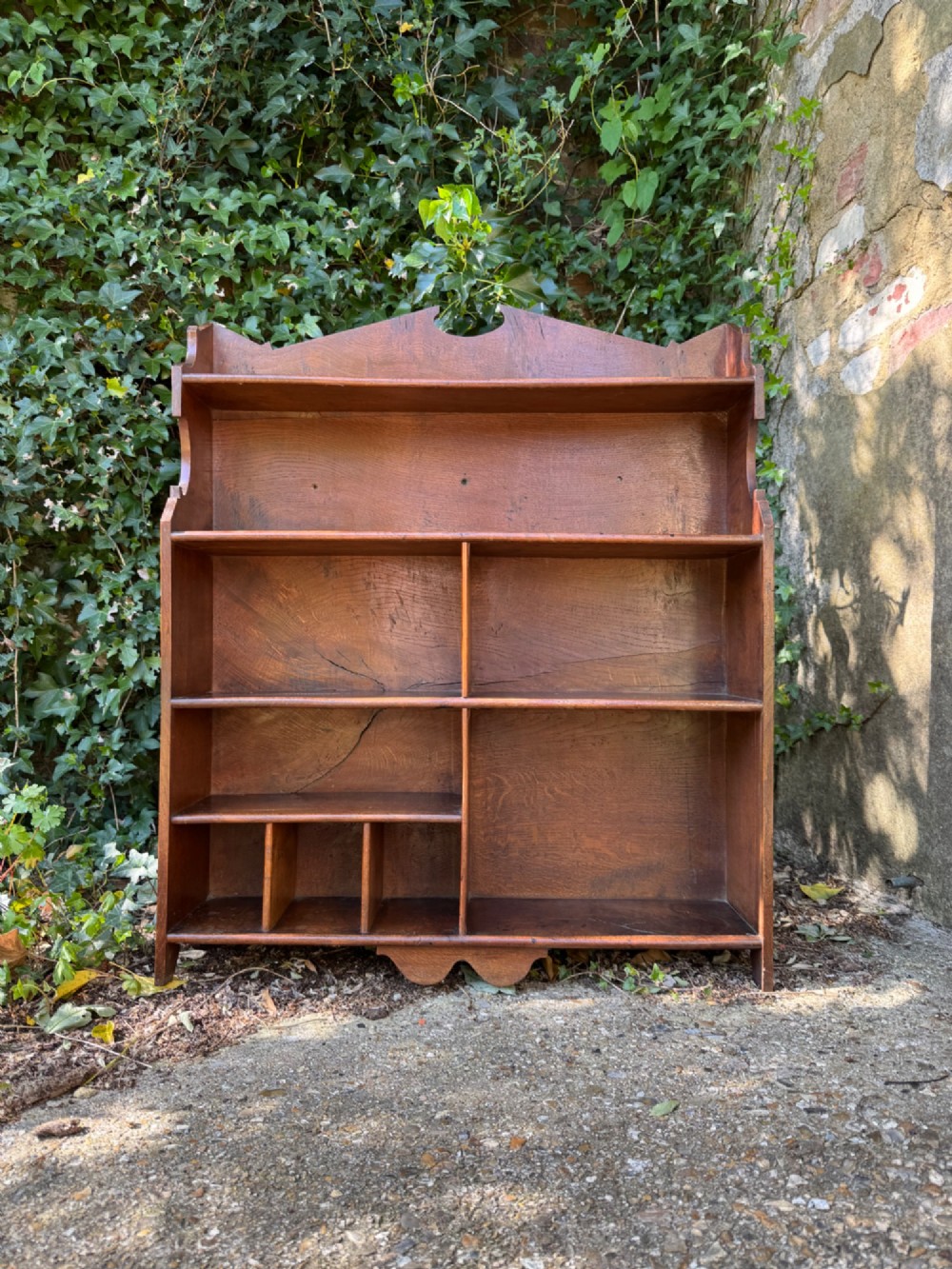 A small antique oak open bookcase featuring multiple shelf compartments, lower cubbies, and shaped side uprights. View II