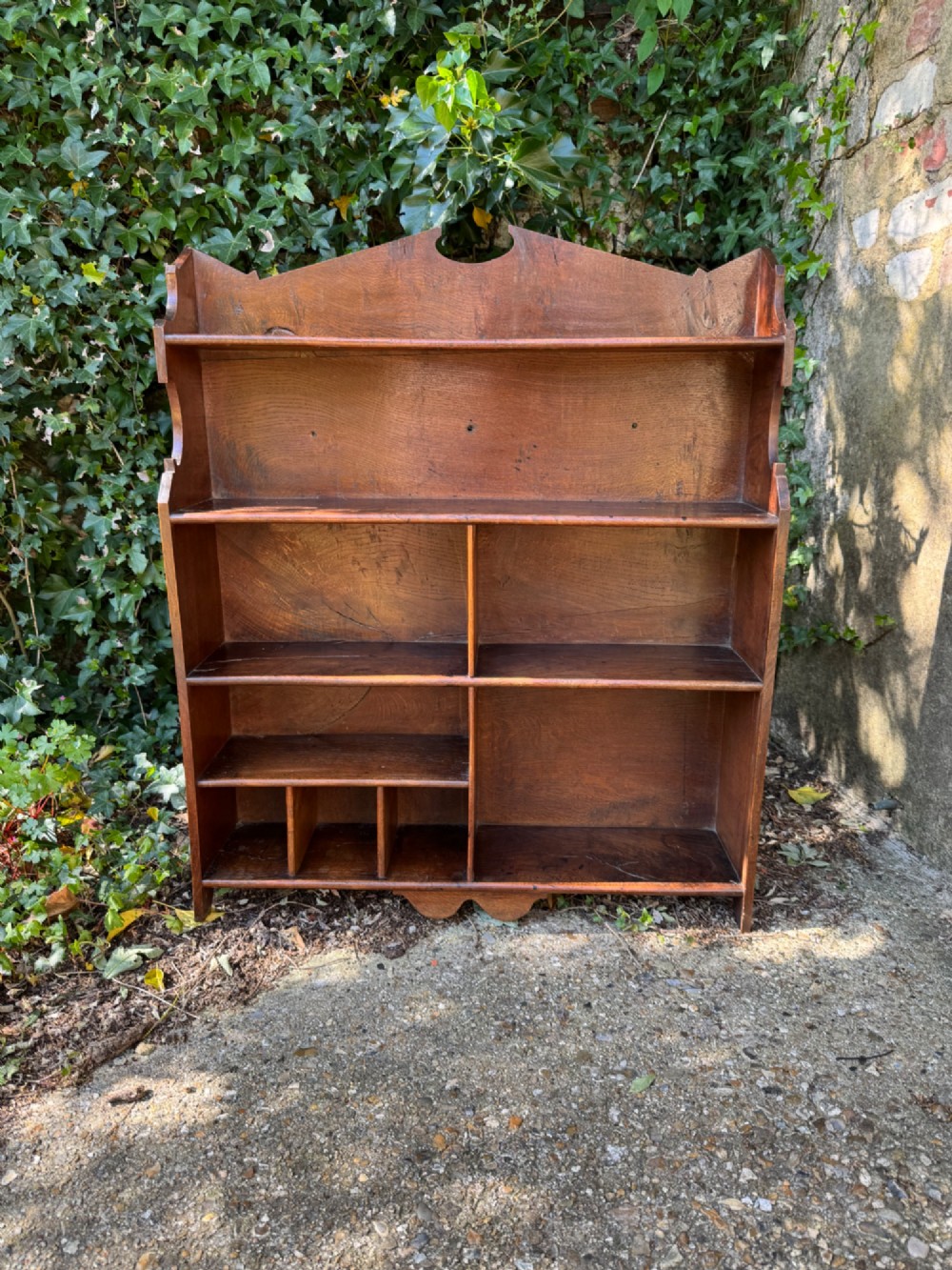 A small antique oak open bookcase featuring multiple shelf compartments, lower cubbies, and shaped side uprights. View III