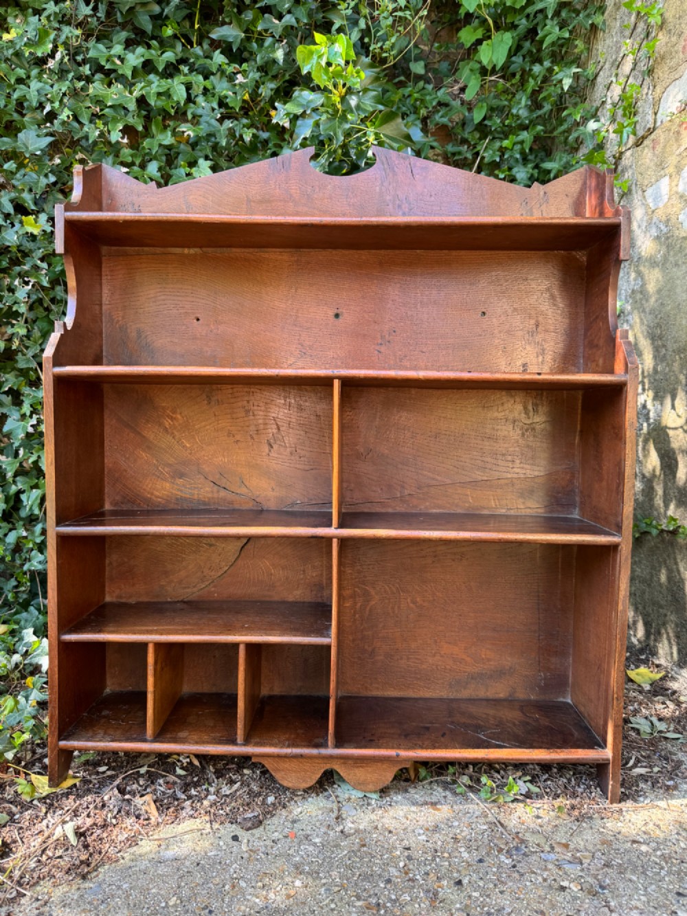 A small antique oak open bookcase featuring multiple shelf compartments, lower cubbies, and shaped side uprights. View IV