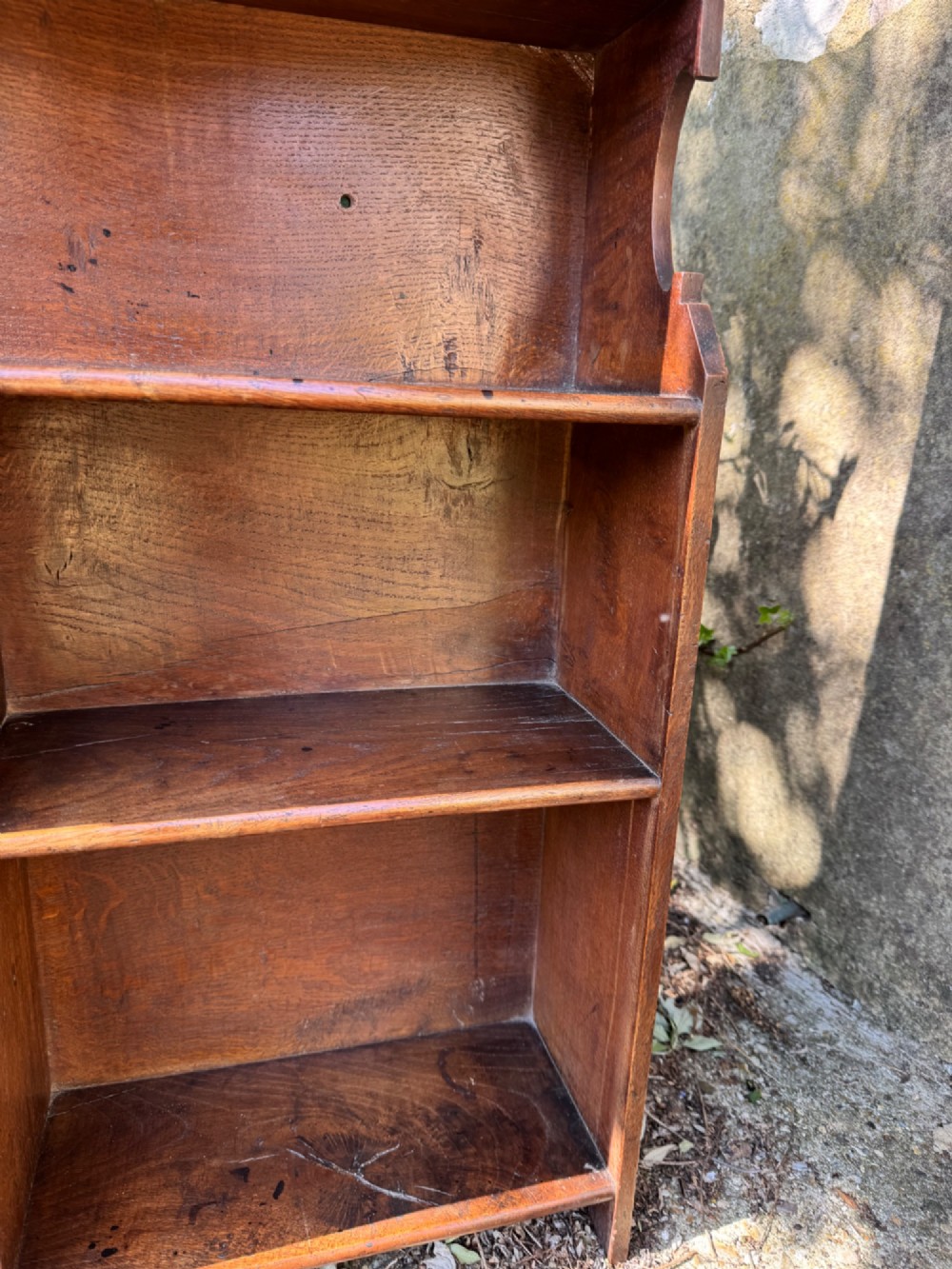 A small antique oak open bookcase featuring multiple shelf compartments, lower cubbies, and shaped side uprights. View V