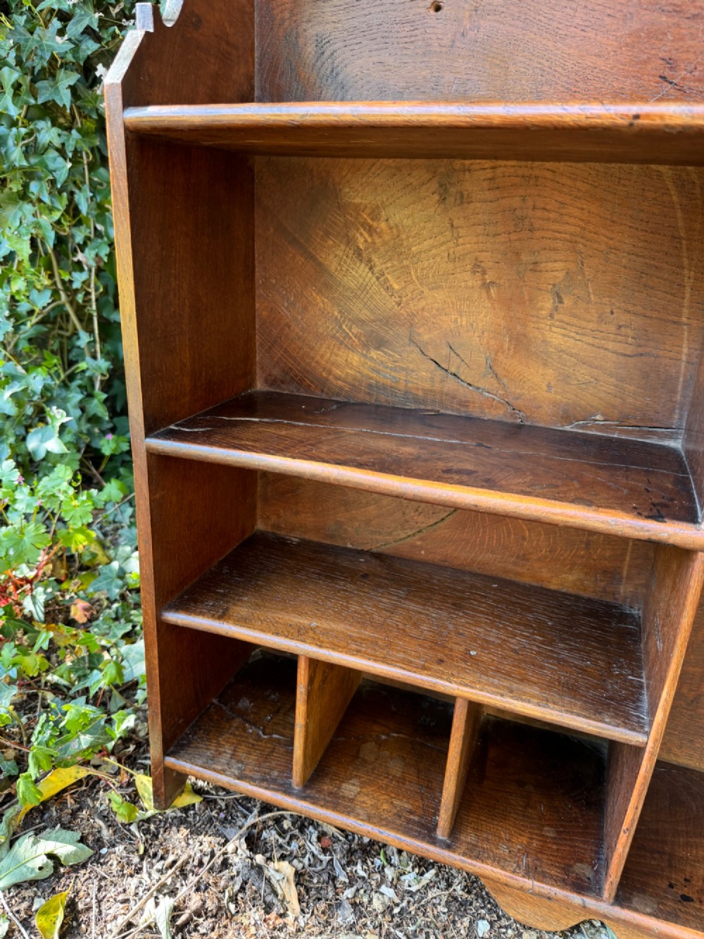 A small antique oak open bookcase featuring multiple shelf compartments, lower cubbies, and shaped side uprights. View VI