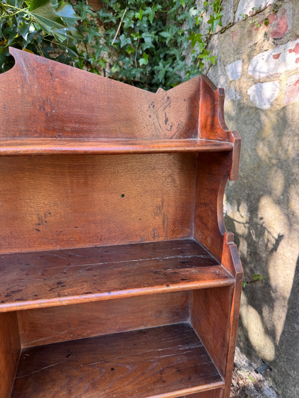A small antique oak open bookcase featuring multiple shelf compartments, lower cubbies, and shaped side uprights. View VIII
