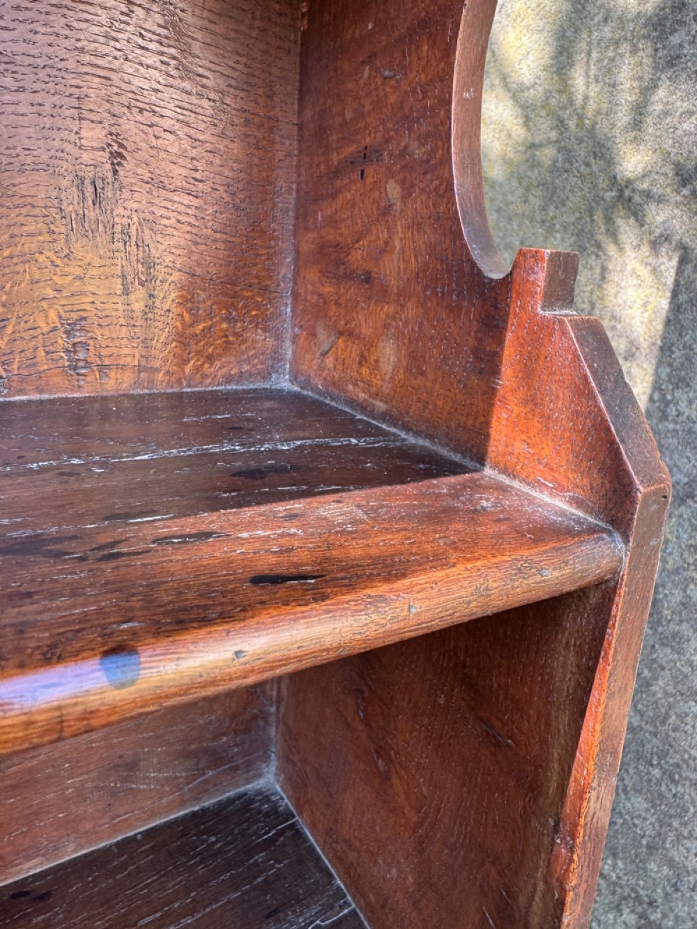 A small antique oak open bookcase featuring multiple shelf compartments, lower cubbies, and shaped side uprights. View IX