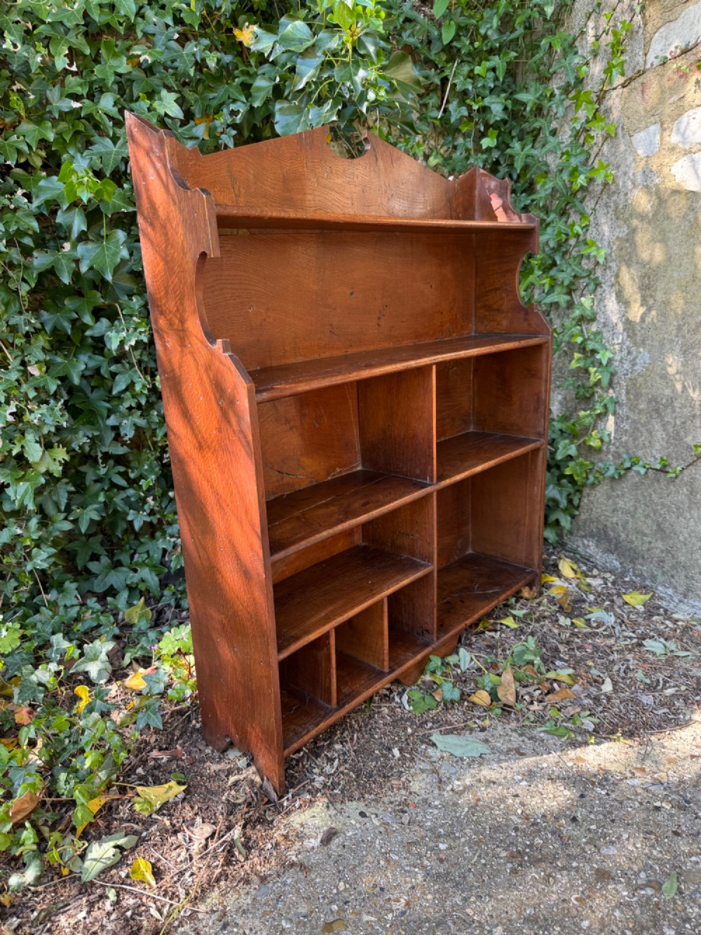 A small antique oak open bookcase featuring multiple shelf compartments, lower cubbies, and shaped side uprights. View XI