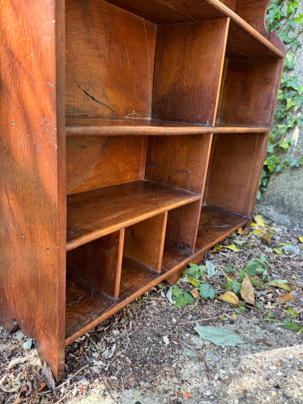 A small antique oak open bookcase featuring multiple shelf compartments, lower cubbies, and shaped side uprights. View XII