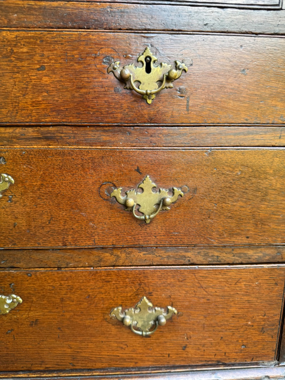 An antique warm brown oak bureau bookcase featuring twin fielded panel upper doors, a slant-front desk, and multiple drawers with brass hardware. View VIII