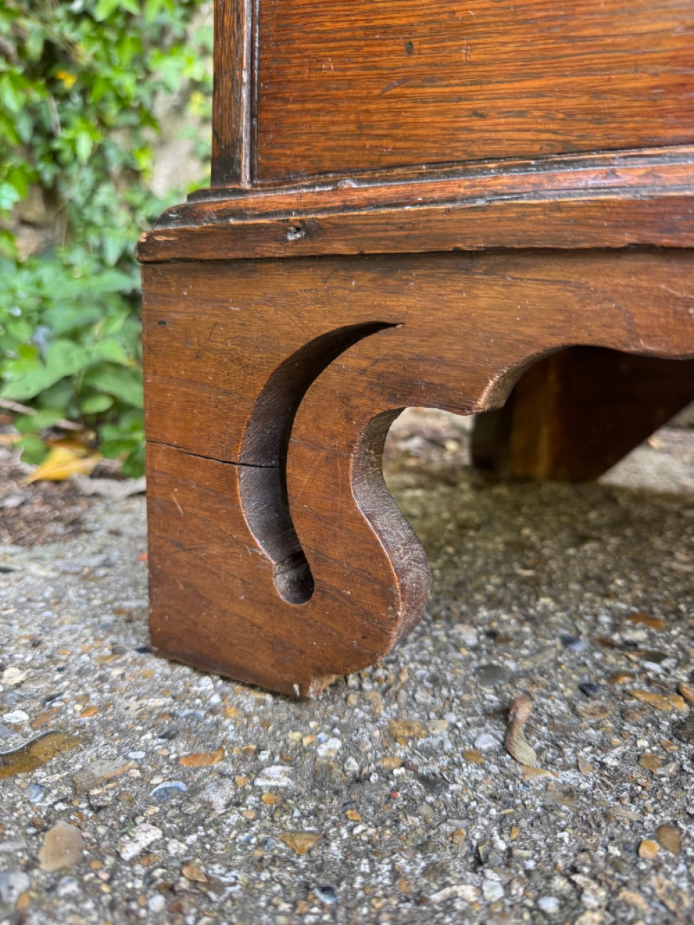 An antique warm brown oak bureau bookcase featuring twin fielded panel upper doors, a slant-front desk, and multiple drawers with brass hardware. View X