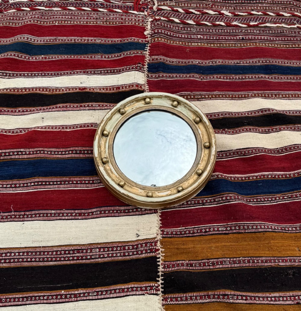 A circular antique convex mirror featuring a gilded and painted frame decorated with spherical balls along the inner rim. View III