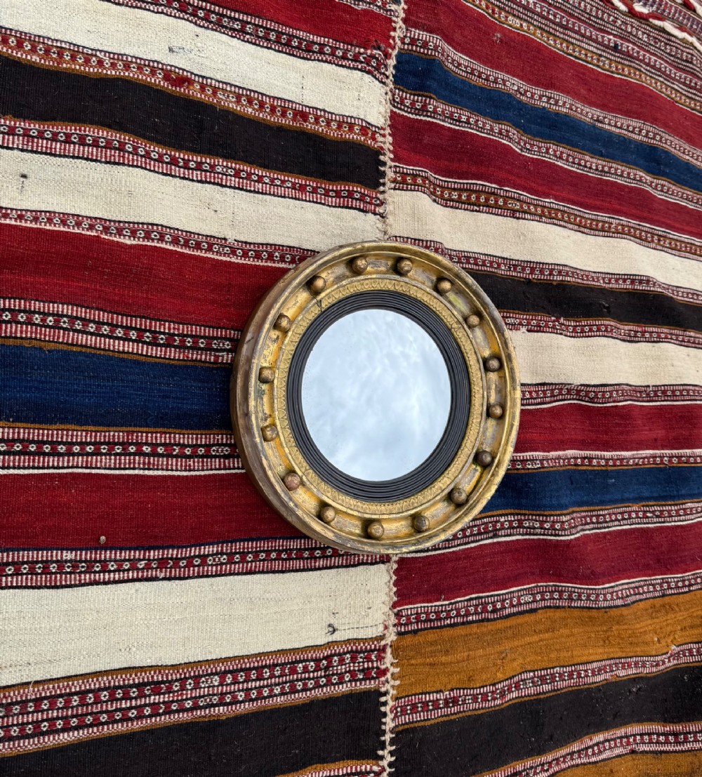 A circular antique giltwood convex mirror featuring a sphere-adorned outer frame and a dark reeded inner slip. View II