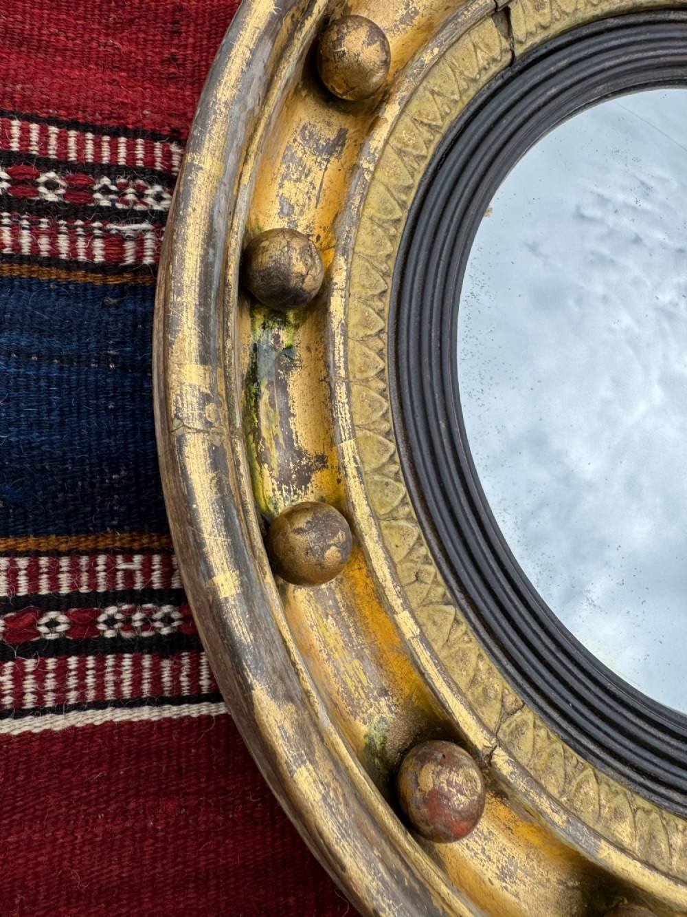 A circular antique giltwood convex mirror featuring a sphere-adorned outer frame and a dark reeded inner slip. View III