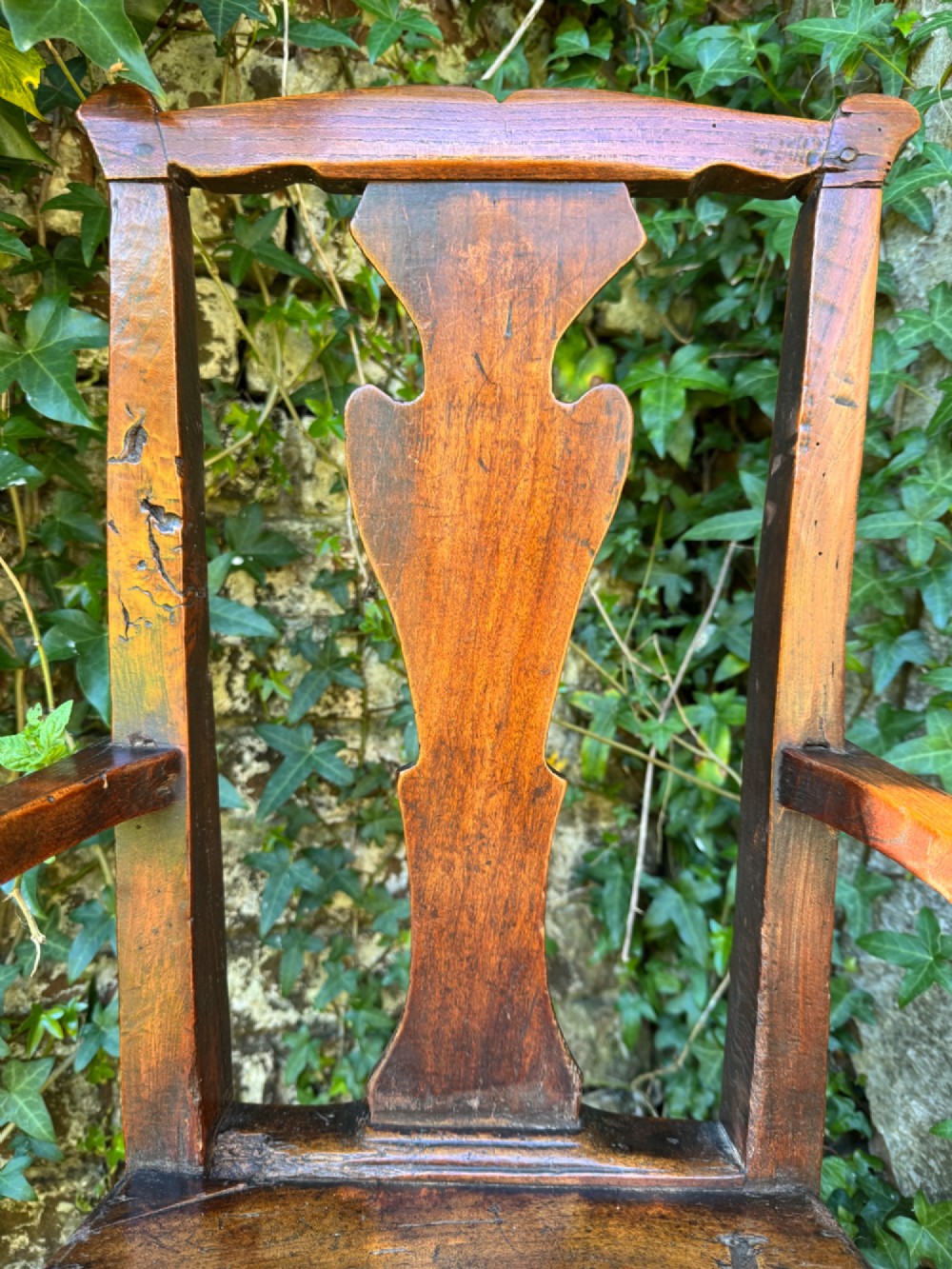 A dark brown Georgian wooden high chair with a central splat back, shaped armrests, square legs, and low wooden stretchers. View IV