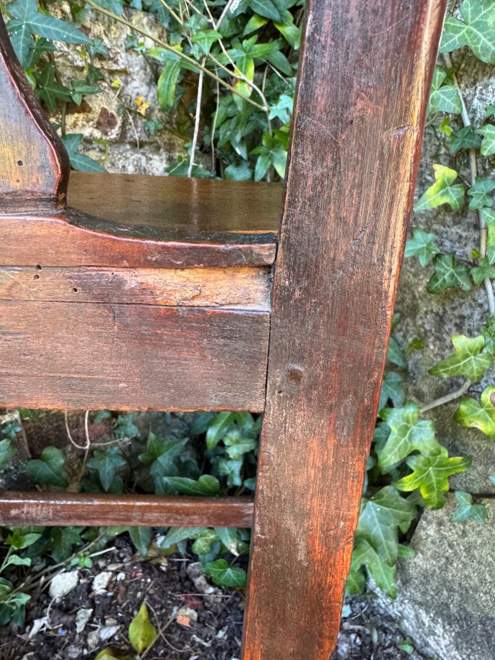 A dark brown Georgian wooden high chair with a central splat back, shaped armrests, square legs, and low wooden stretchers. View X