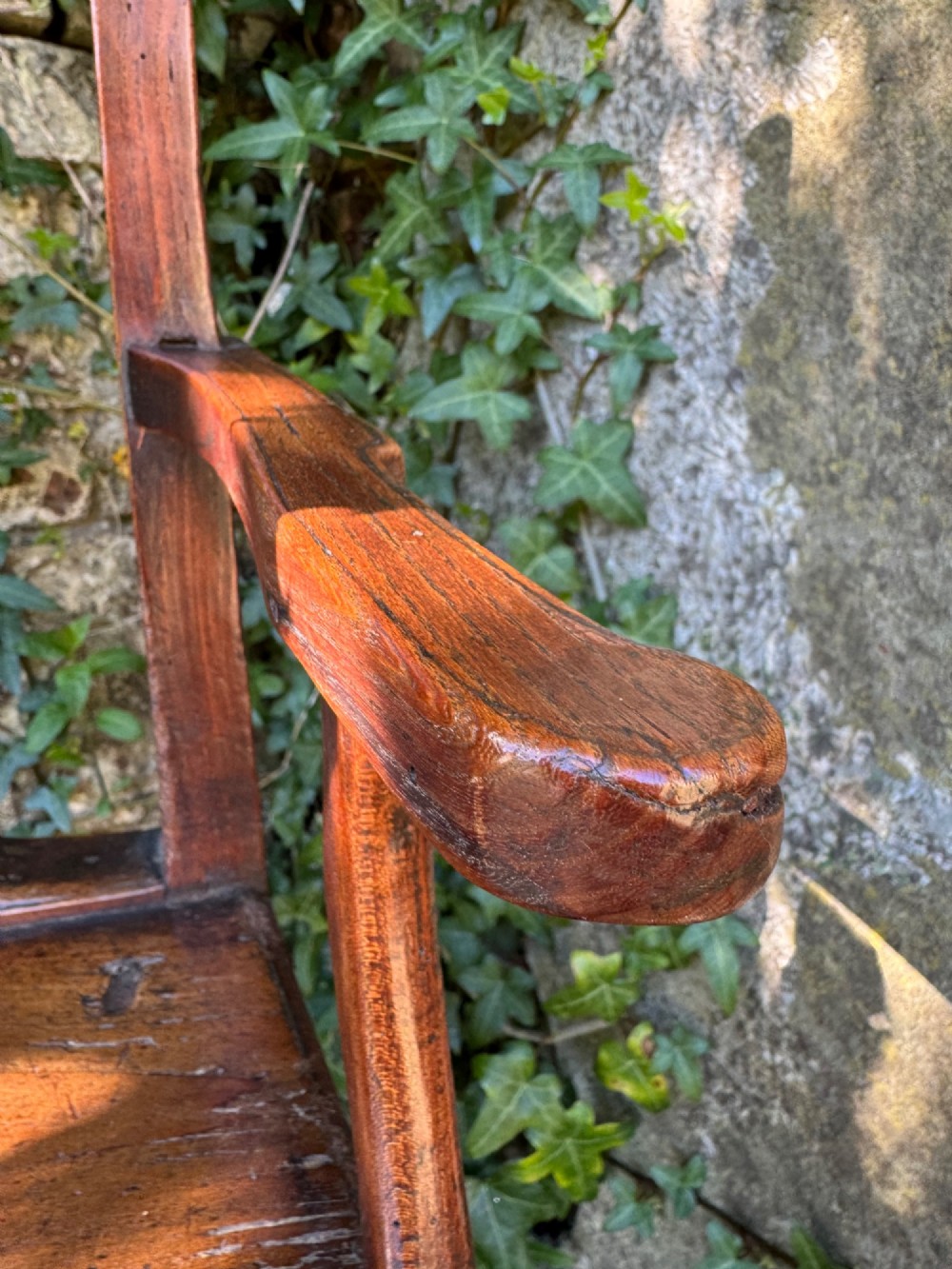 A dark brown Georgian wooden high chair with a central splat back, shaped armrests, square legs, and low wooden stretchers. View XII