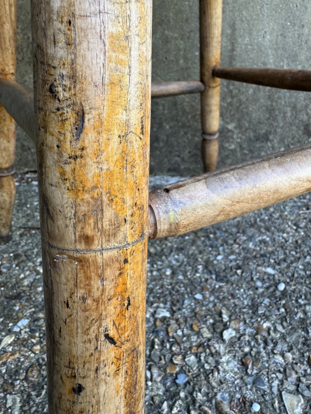 A rustic circular wooden stool featuring four splayed turned legs supported by horizontal timber stretchers. View XII