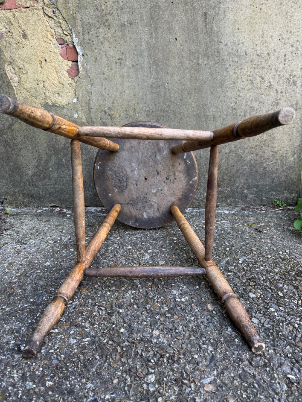 A rustic circular wooden stool featuring four splayed turned legs supported by horizontal timber stretchers. View XIV