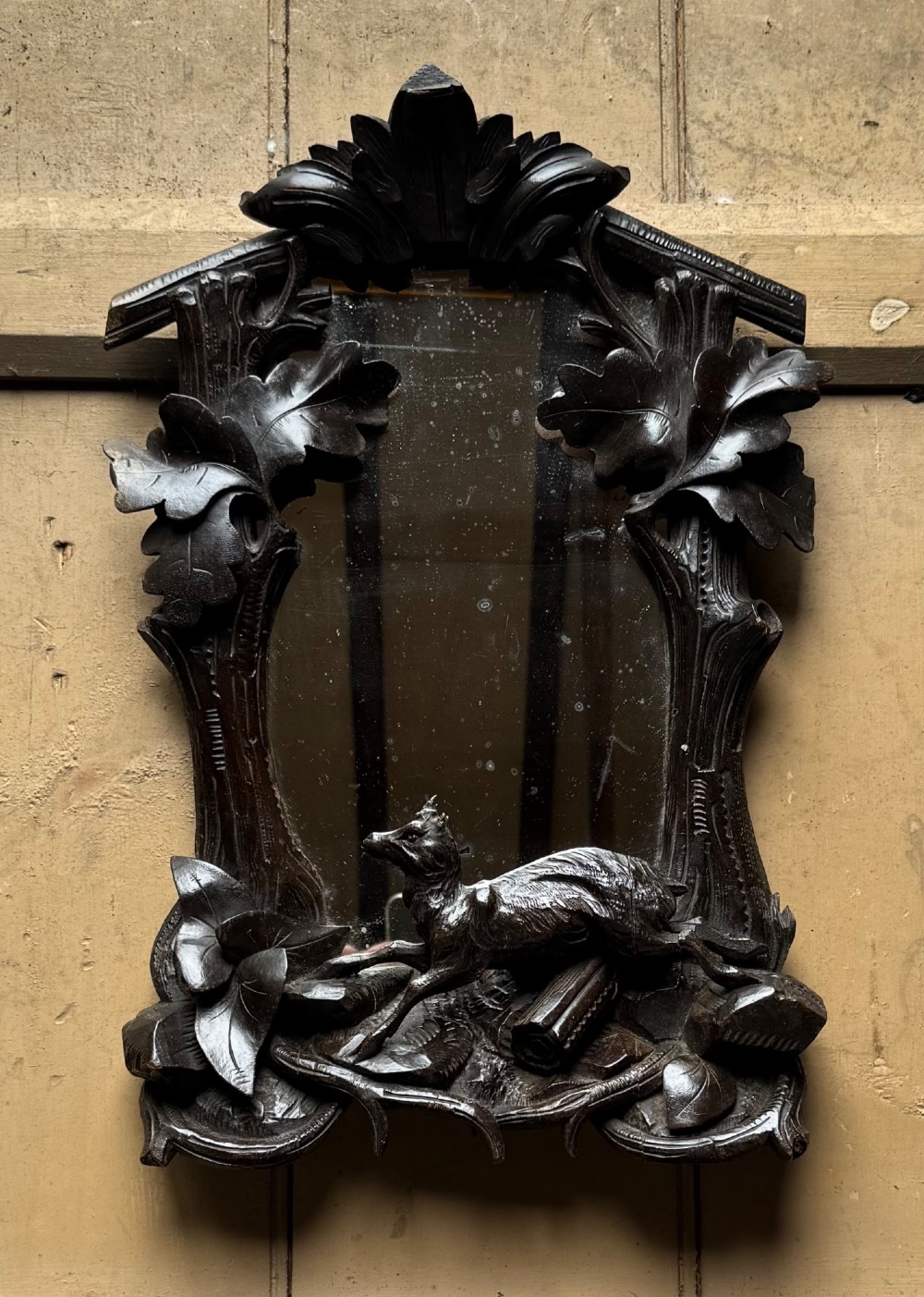 A dark hand-carved wooden wall mirror featuring a fox sculpted at the base surrounded by carved oak leaves and branches. View II