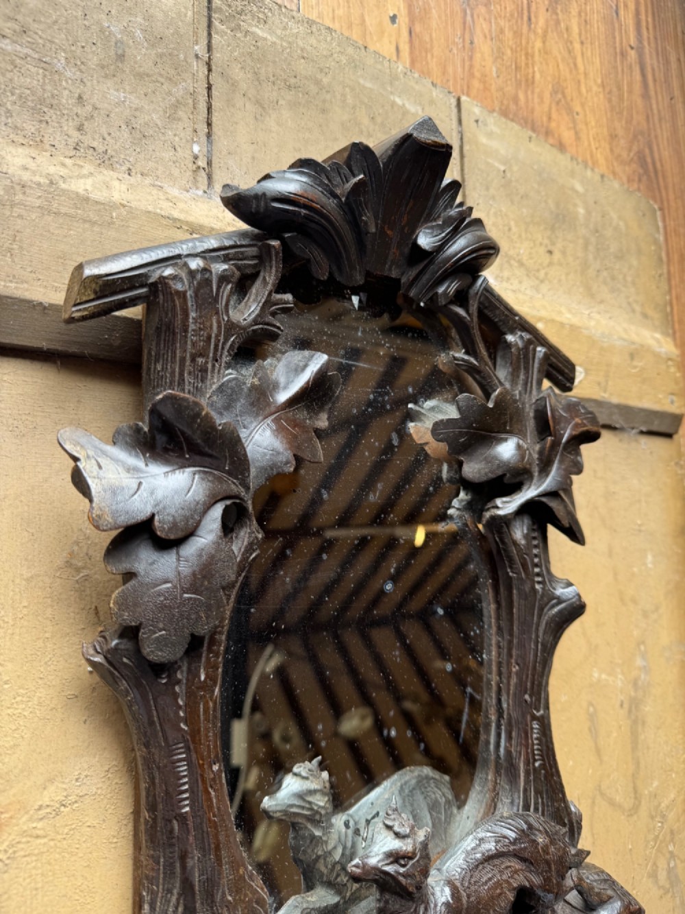 A dark hand-carved wooden wall mirror featuring a fox sculpted at the base surrounded by carved oak leaves and branches. View X