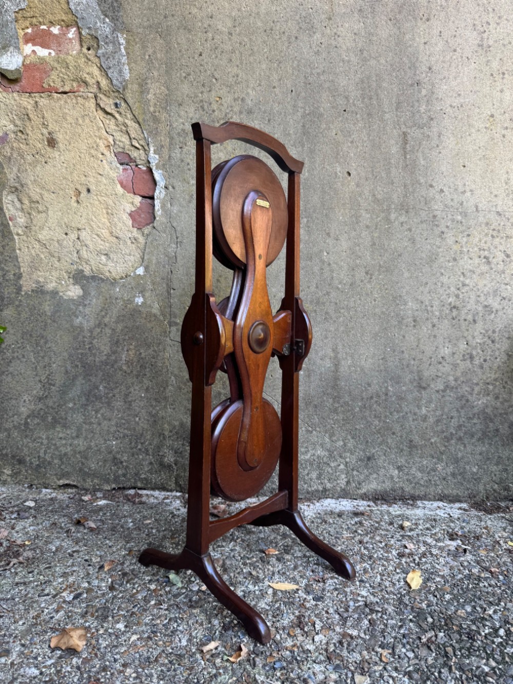An antique mahogany monoplane folding cake stand with five circular wooden trays supported on a vertical frame with arched feet. View IV