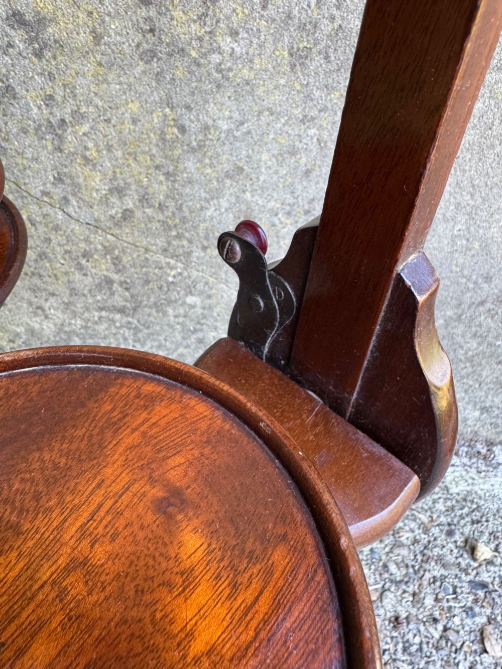 An antique mahogany monoplane folding cake stand with five circular wooden trays supported on a vertical frame with arched feet. View V