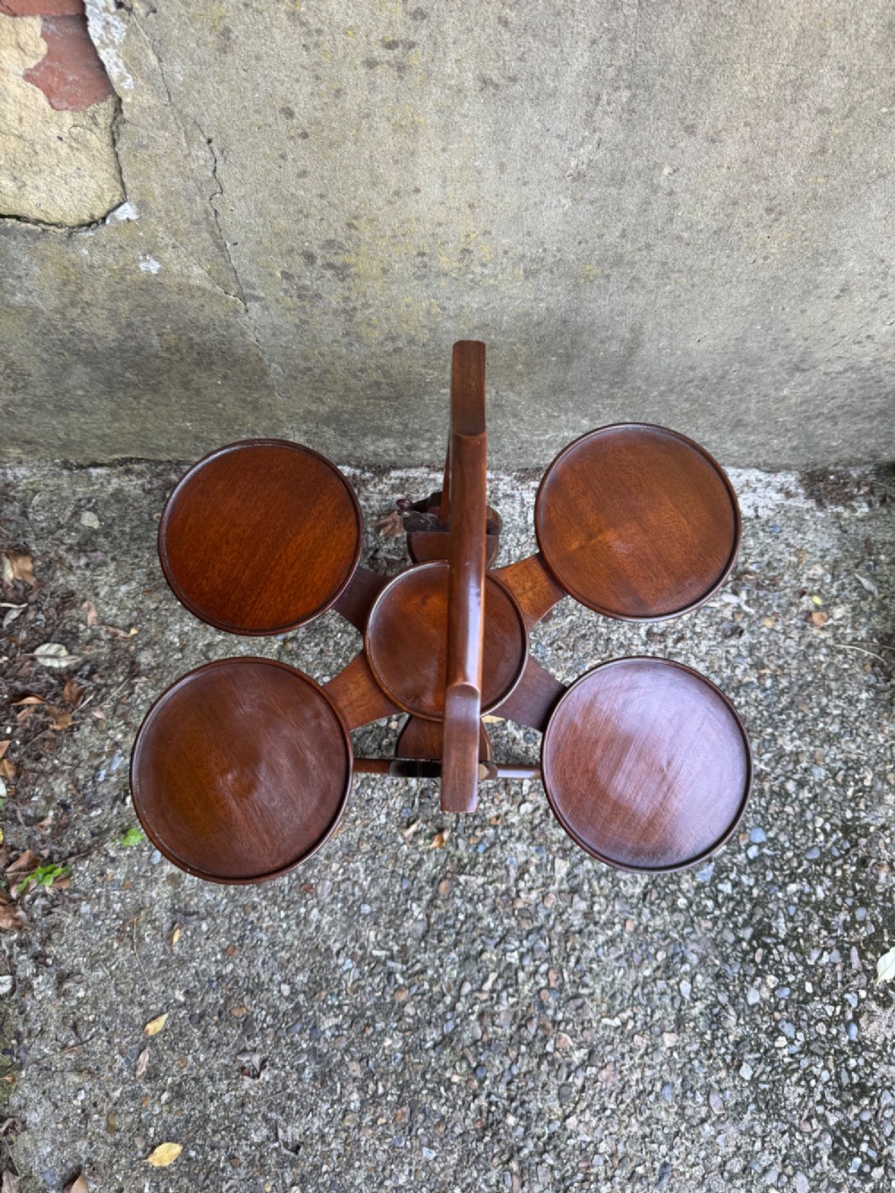 An antique mahogany monoplane folding cake stand with five circular wooden trays supported on a vertical frame with arched feet. View IX