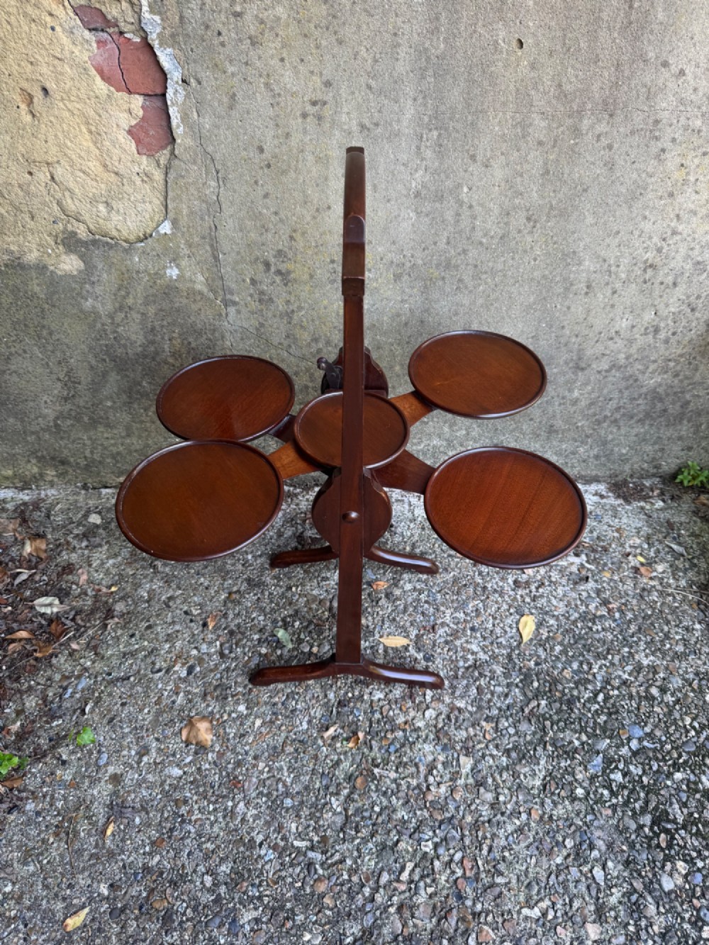 An antique mahogany monoplane folding cake stand with five circular wooden trays supported on a vertical frame with arched feet. View XIII