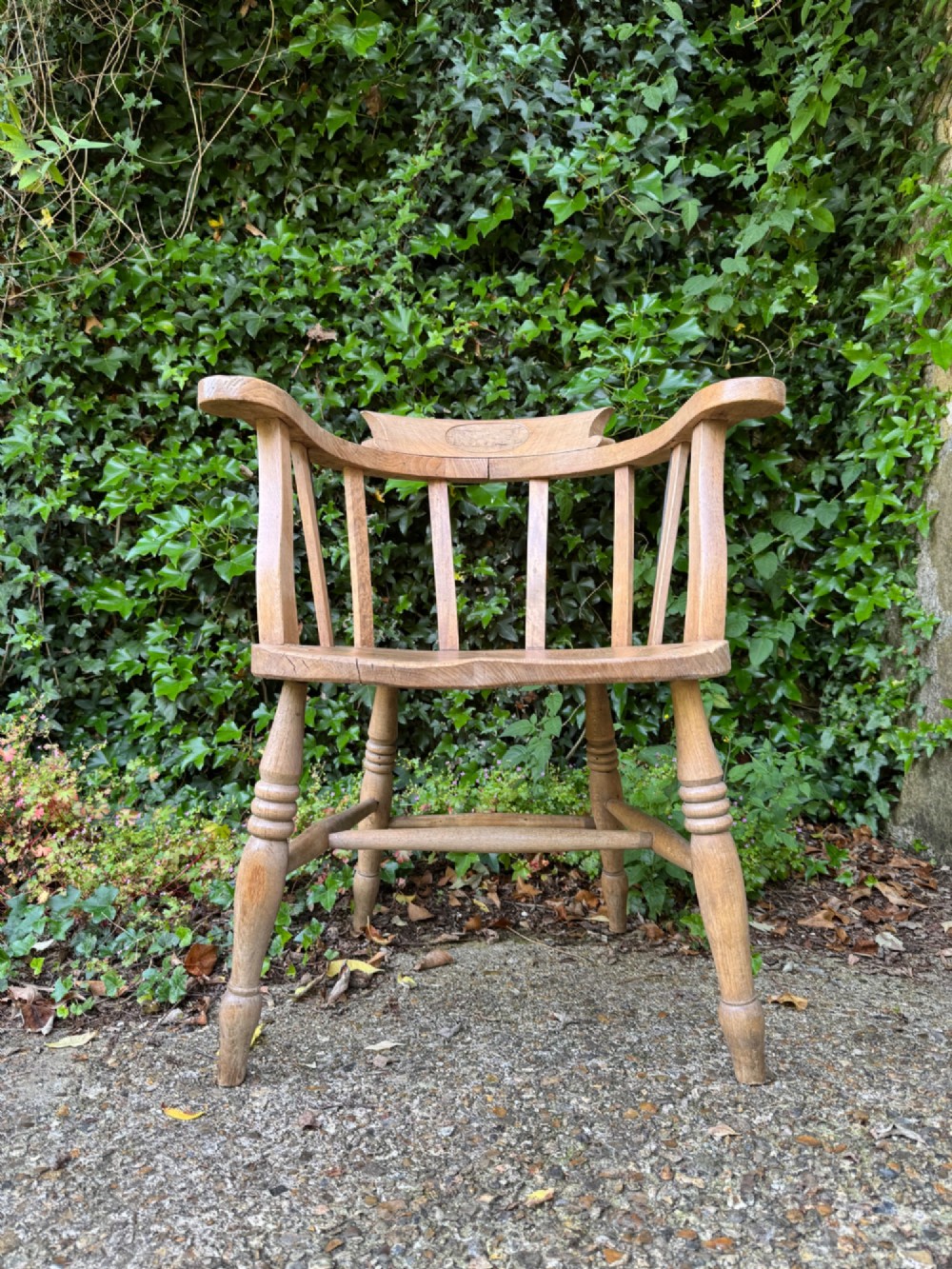 A low-backed antique oak captains armchair featuring turned legs, an H-stretcher, and vertical spindles supporting a broad curved armrest rail. View II