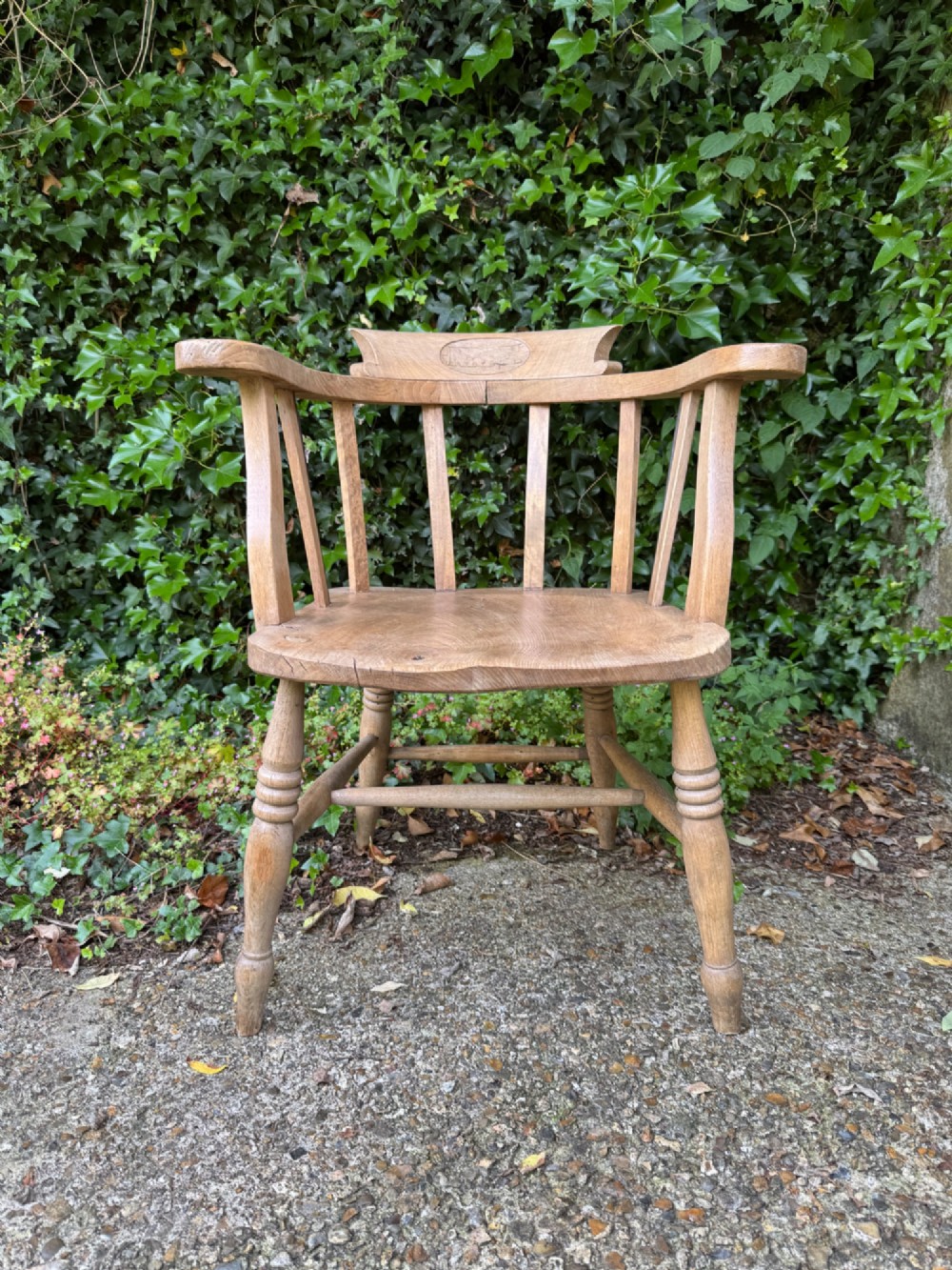 A low-backed antique oak captains armchair featuring turned legs, an H-stretcher, and vertical spindles supporting a broad curved armrest rail. View III