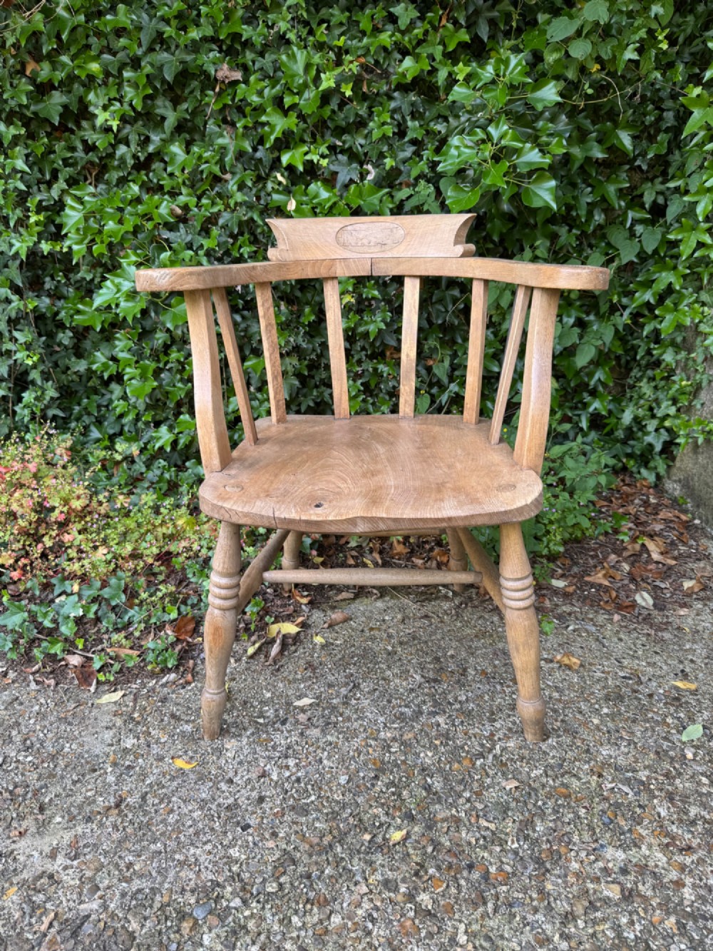 A low-backed antique oak captains armchair featuring turned legs, an H-stretcher, and vertical spindles supporting a broad curved armrest rail. View IV