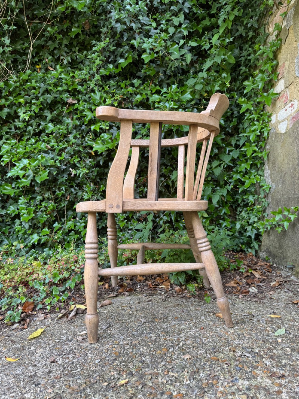 A low-backed antique oak captains armchair featuring turned legs, an H-stretcher, and vertical spindles supporting a broad curved armrest rail. View IX
