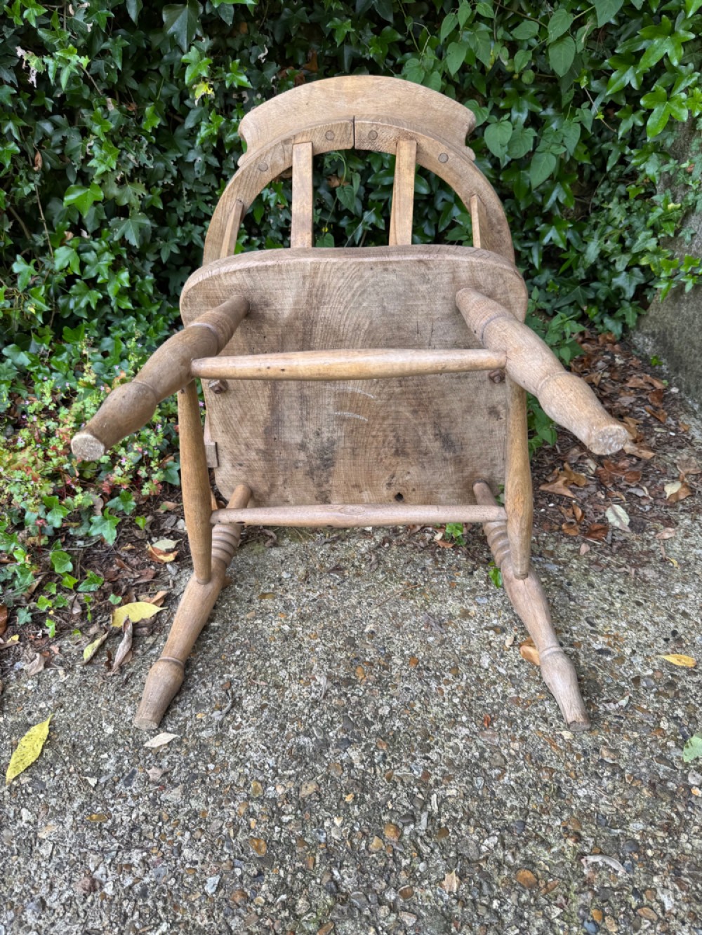 A low-backed antique oak captains armchair featuring turned legs, an H-stretcher, and vertical spindles supporting a broad curved armrest rail. View XII