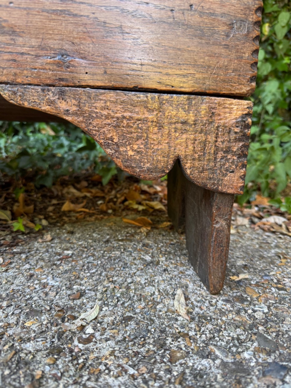 An antique dark oak plank coffer featuring notch-carved vertical edges, V-cut end feet, and a central iron lockplate. View V
