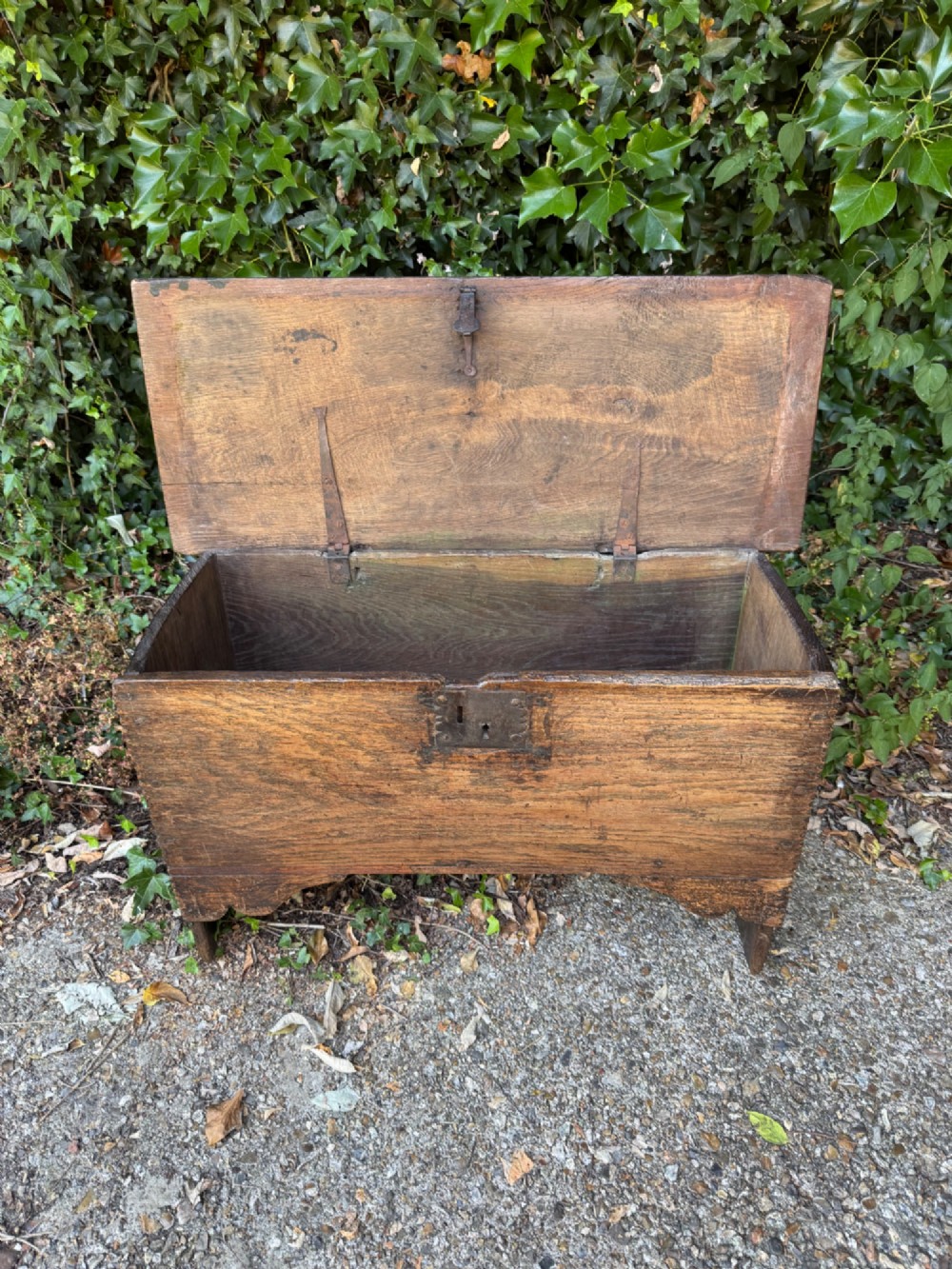 An antique dark oak plank coffer featuring notch-carved vertical edges, V-cut end feet, and a central iron lockplate. View VI