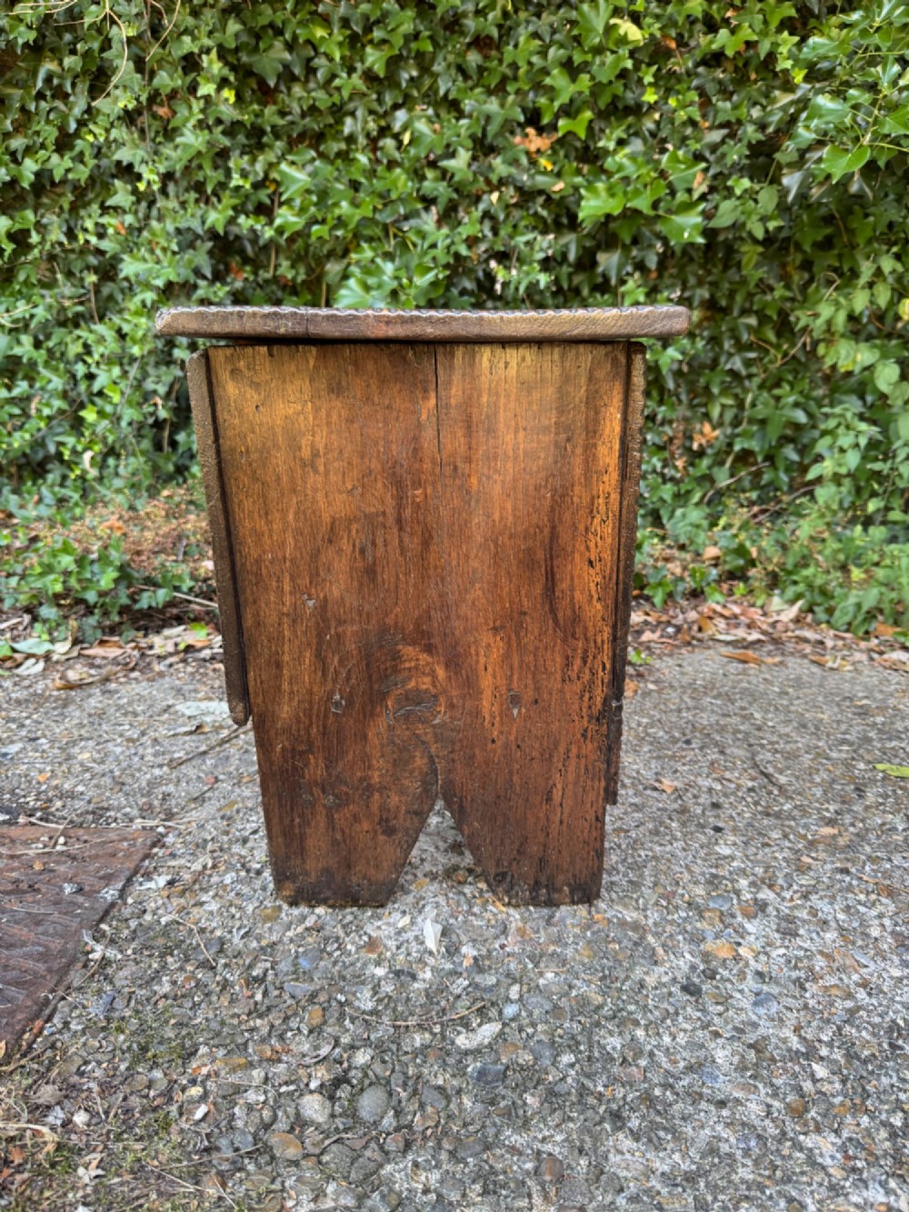 An antique dark oak plank coffer featuring notch-carved vertical edges, V-cut end feet, and a central iron lockplate. View IX