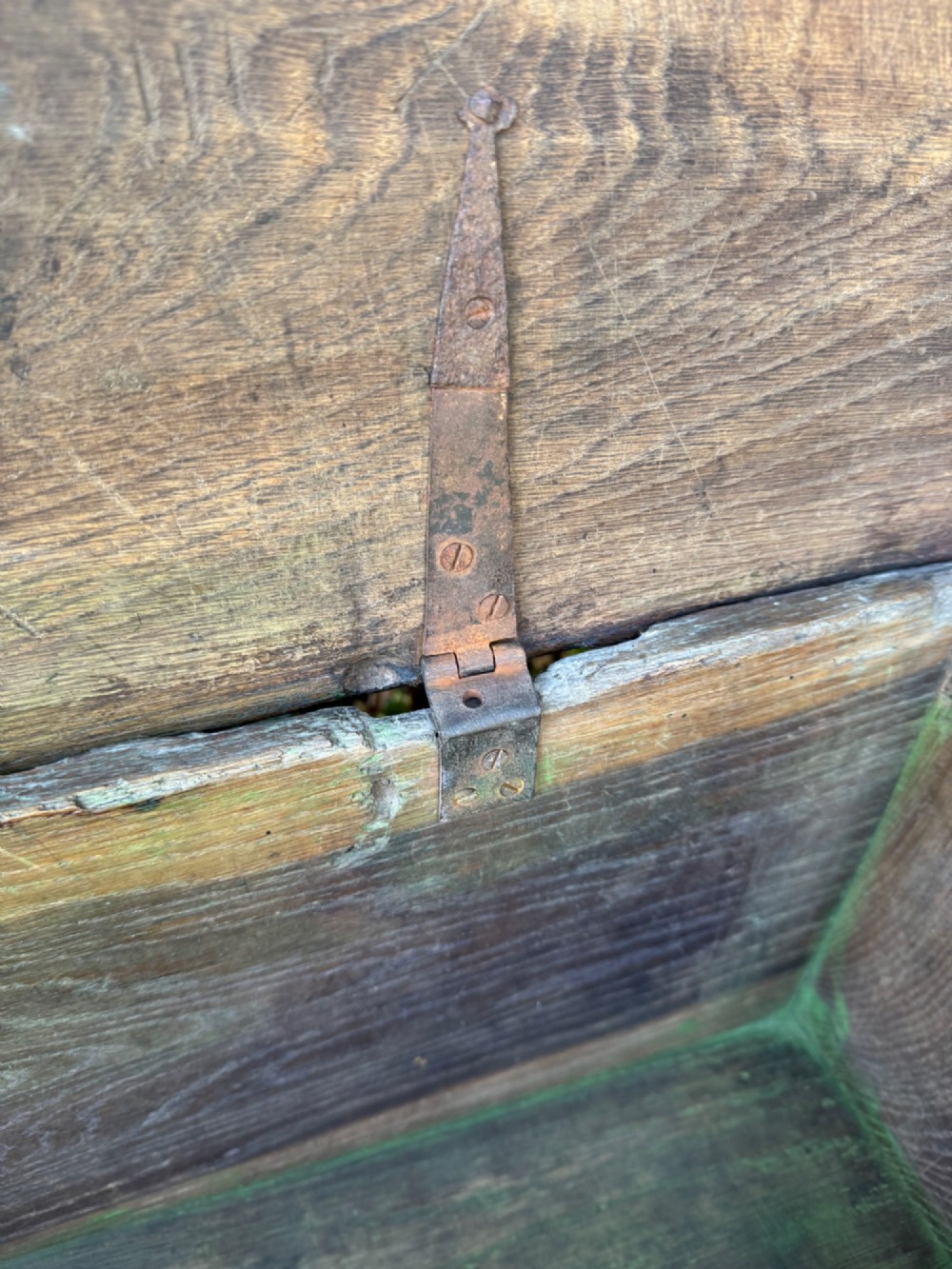 An antique dark oak plank coffer featuring notch-carved vertical edges, V-cut end feet, and a central iron lockplate. View XIII