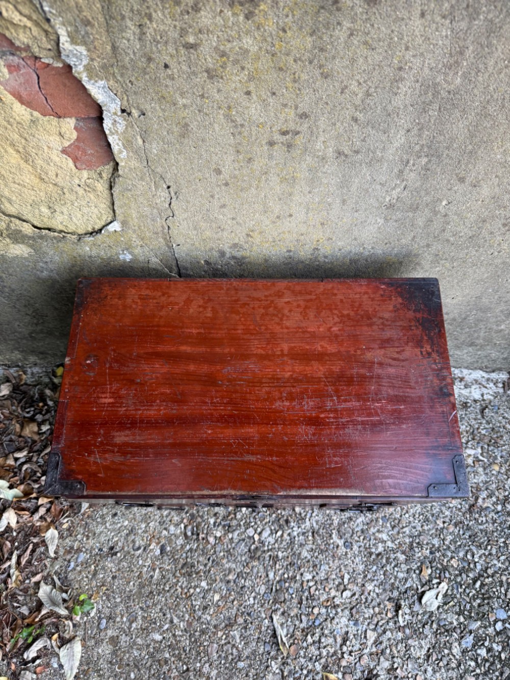 A reddish brown lacquered Japanese wooden tansu chest featuring iron corner plates, circular lock fittings, side carrying handles, and multiple graduated drawers. View VIII