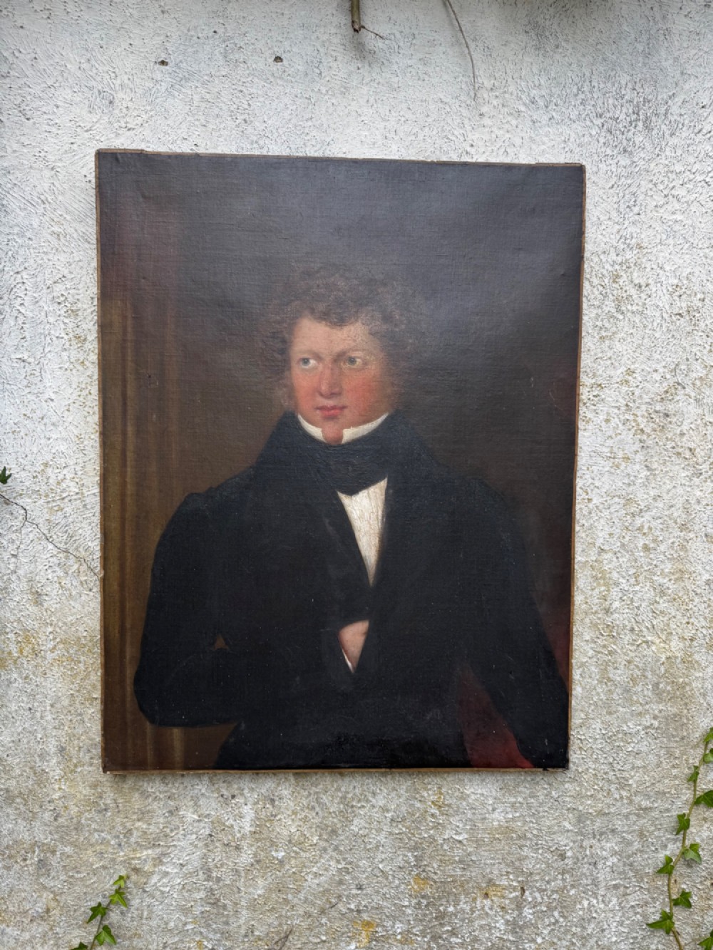 An unframed antique oil painting on canvas depicting a gentleman in a high black cravat and coat against a muted brown background.