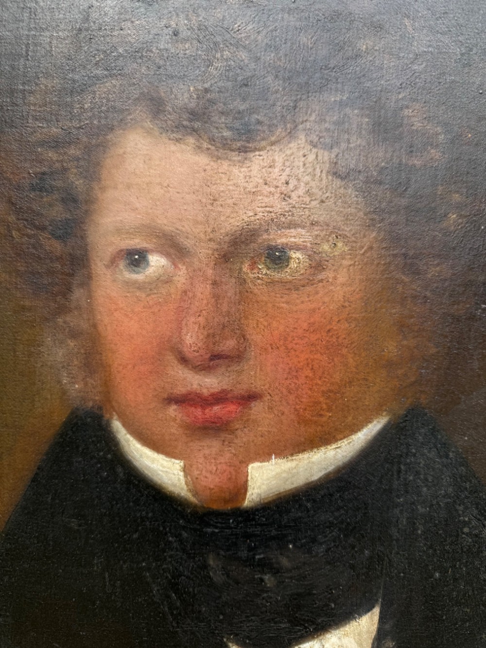 An unframed antique oil painting on canvas depicting a gentleman in a high black cravat and coat against a muted brown background. View IV
