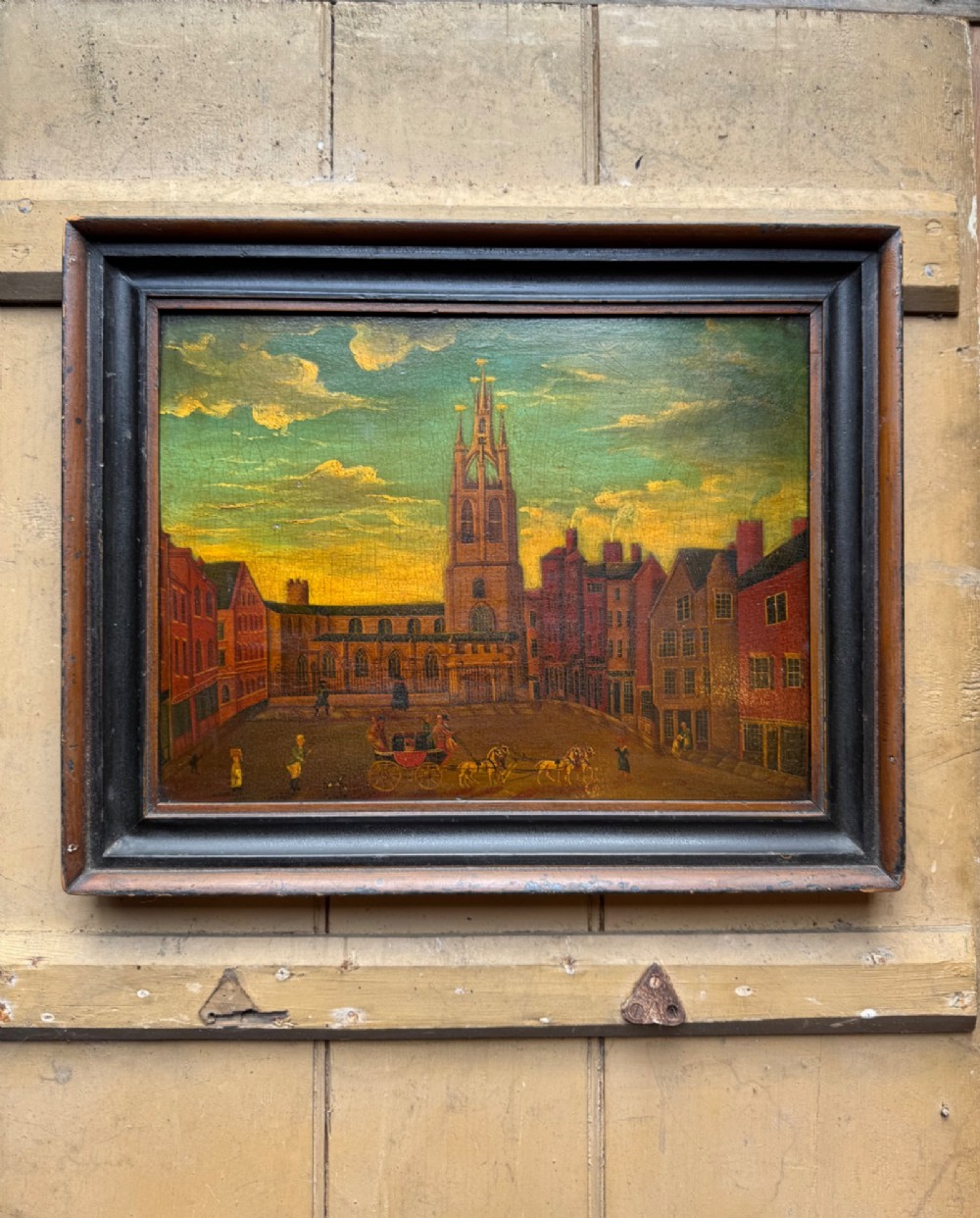 An antique naive oil painting depicting St Nicholas Square in Newcastle with horse-drawn carriages and figures set within a dark wooden frame.