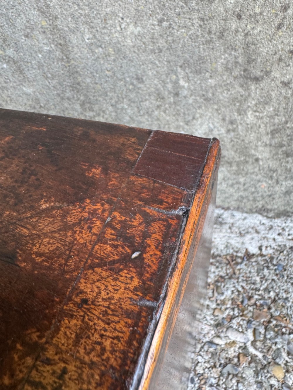 A miniature antique mahogany apprentice chest featuring three drawers with brass oval drop handles and keyhole escutcheons resting on a shaped apron base. View V
