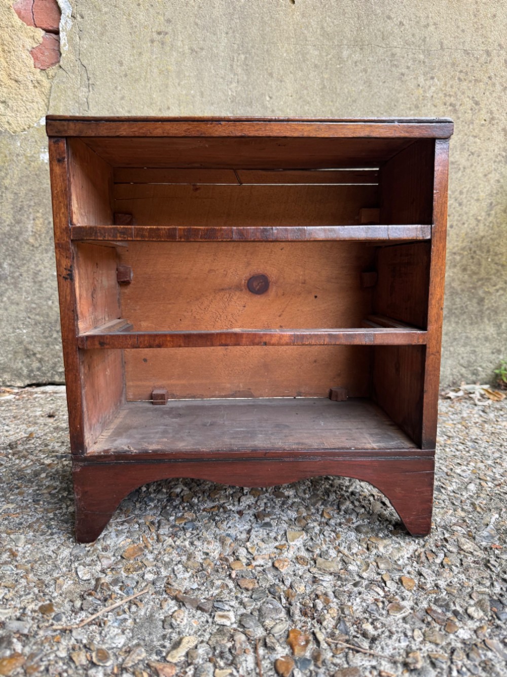 A miniature antique mahogany apprentice chest featuring three drawers with brass oval drop handles and keyhole escutcheons resting on a shaped apron base. View XV