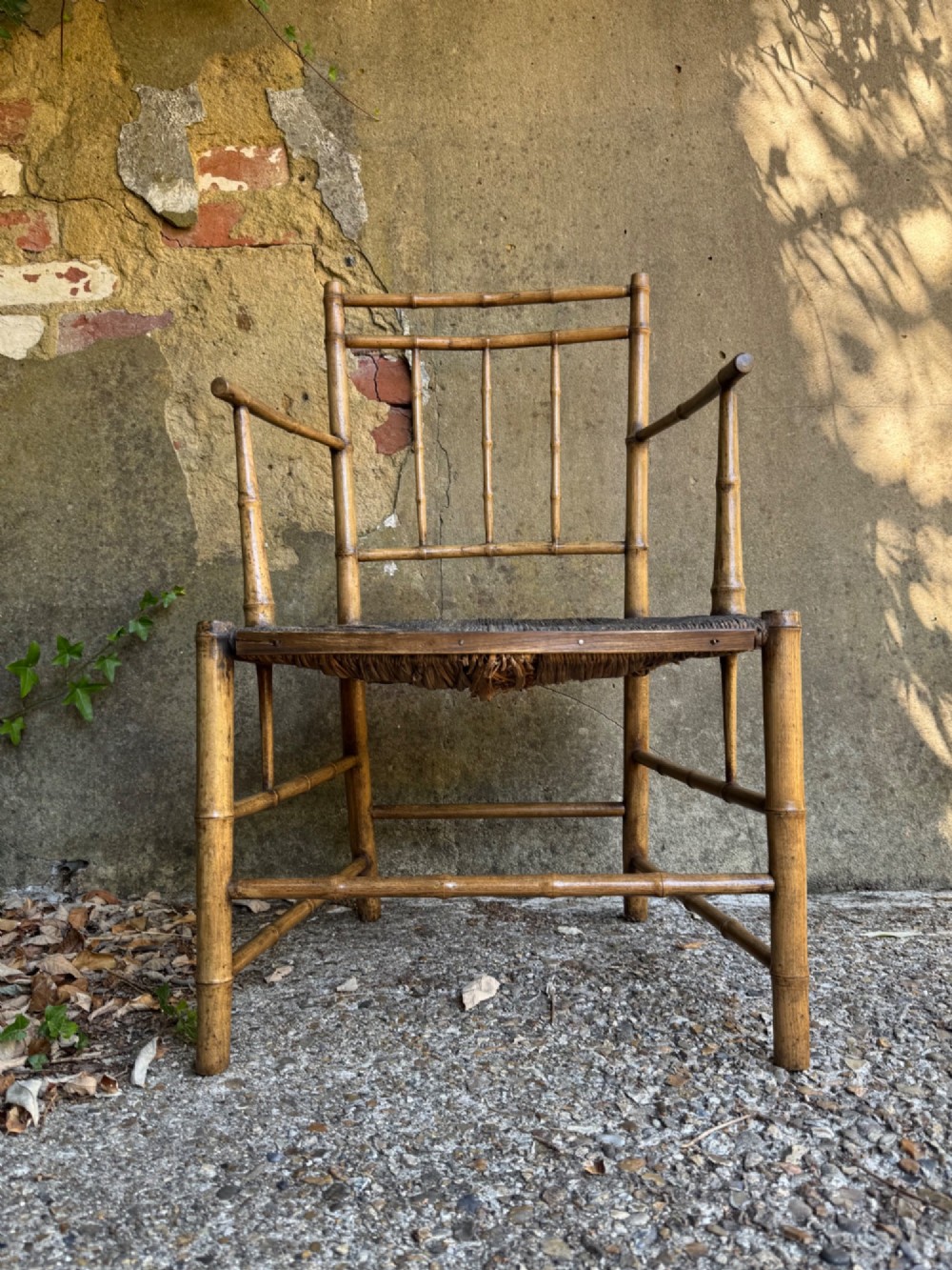 An antique turned wooden armchair with faux-bamboo detailing and a dark woven rush seat. View II