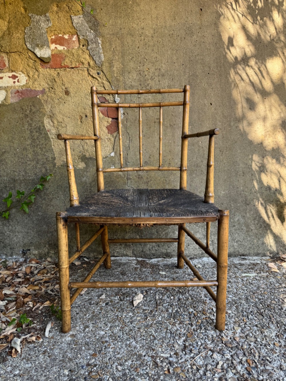 An antique turned wooden armchair with faux-bamboo detailing and a dark woven rush seat. View V