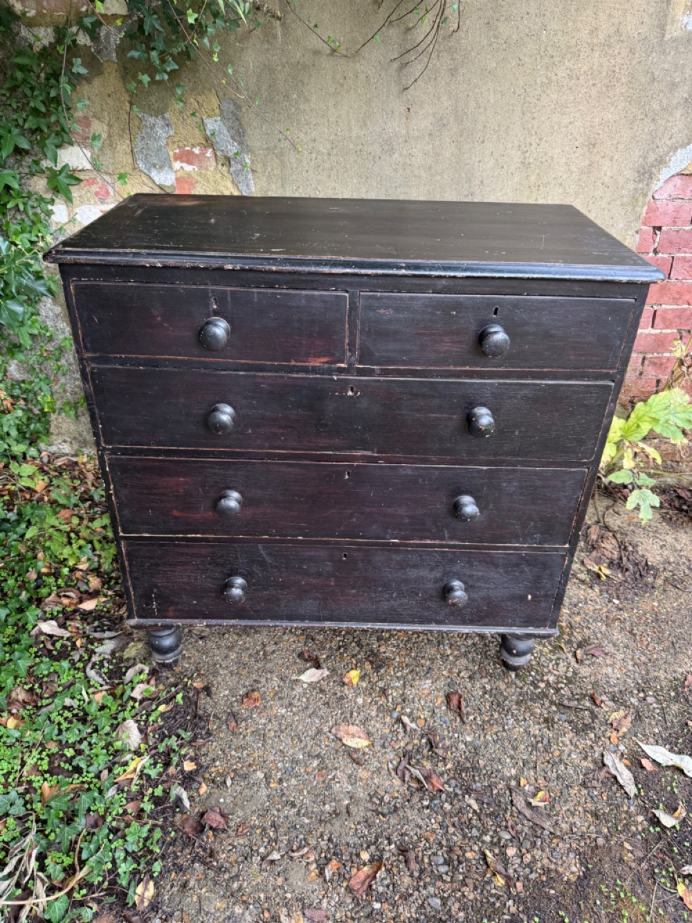 A Victorian dark painted pine chest featuring two short drawers above three long drawers, fitted with turned wooden knobs and supported by turned feet. View III