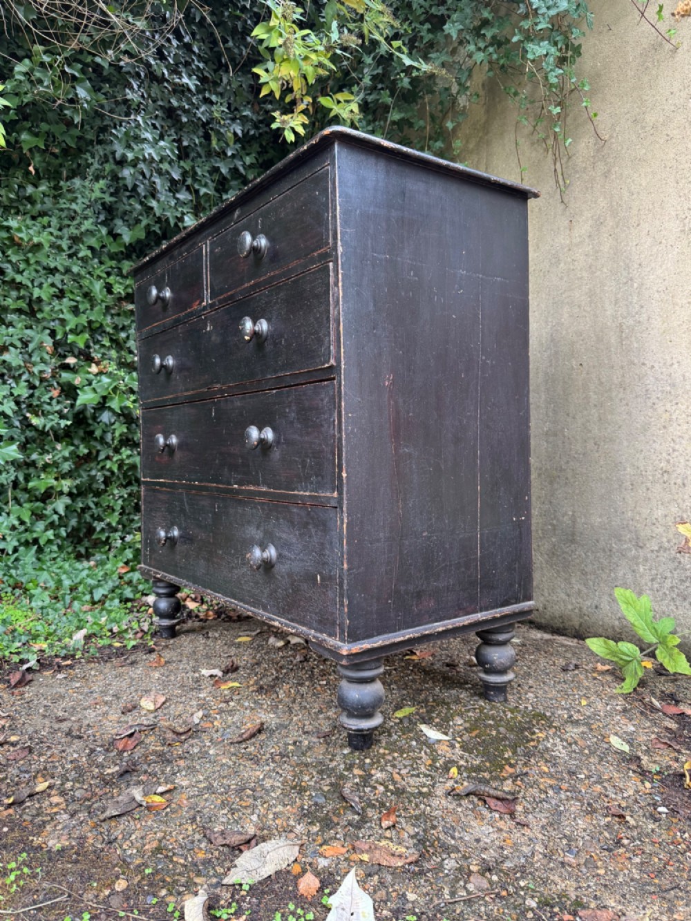 A Victorian dark painted pine chest featuring two short drawers above three long drawers, fitted with turned wooden knobs and supported by turned feet. View IV