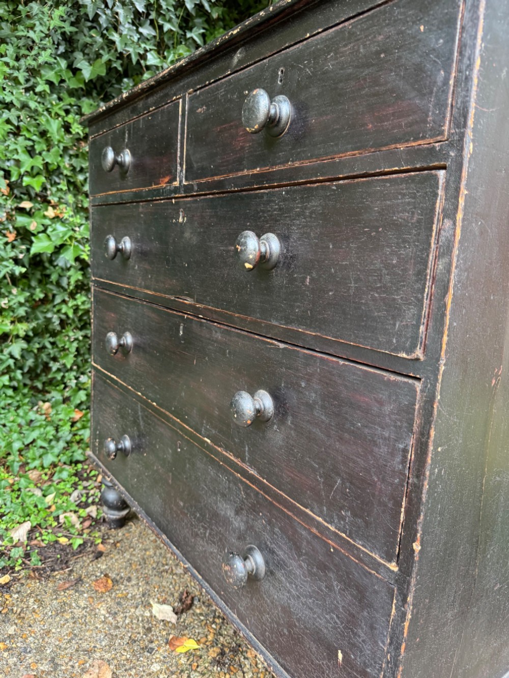A Victorian dark painted pine chest featuring two short drawers above three long drawers, fitted with turned wooden knobs and supported by turned feet. View VIII
