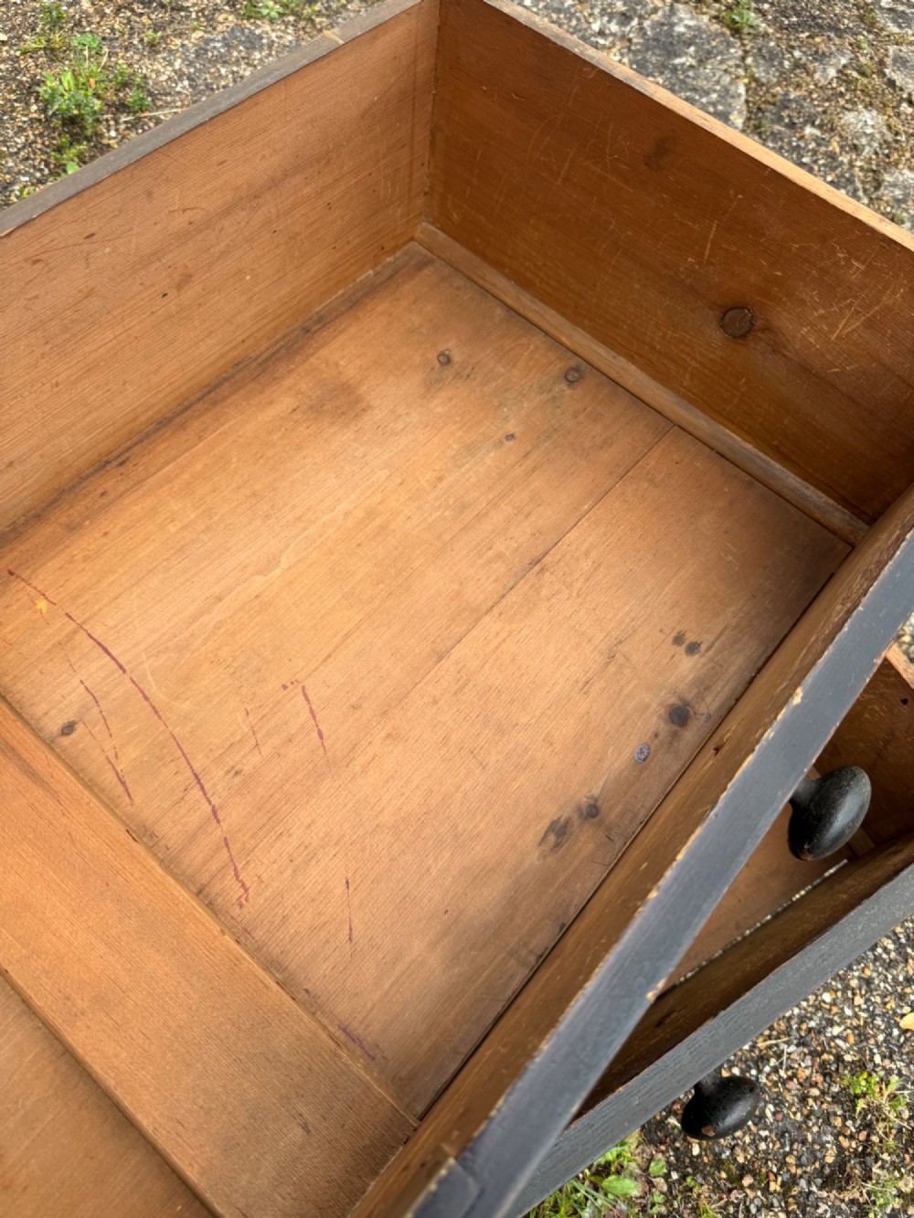 A Victorian dark painted pine chest featuring two short drawers above three long drawers, fitted with turned wooden knobs and supported by turned feet. View XII
