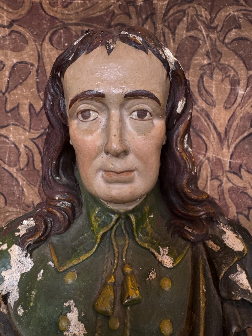 A polychrome painted bust depicting John Milton with long brown hair, a collared shirt with tassels, and a grey socle pedestal base. View IV